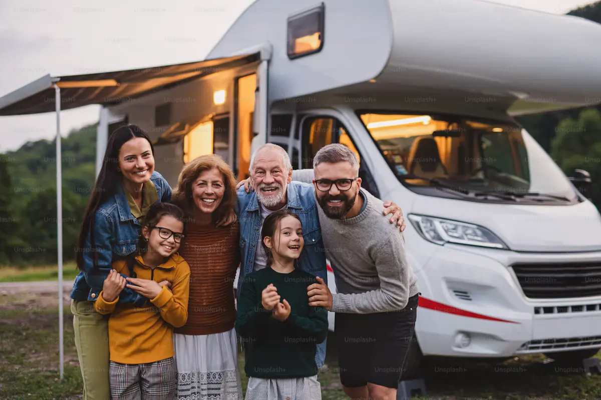 A smiling family standing together in front of an RV